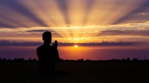 Pessoa em oração contemplando o pôr do sol